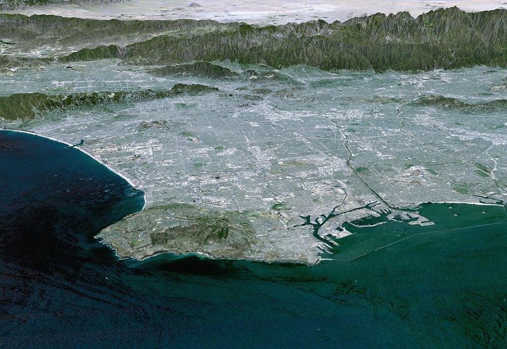 Aerial coastal city view with harbor and mountains Aerial view of a coastal city with mountains in the background and a large harbor area by the ocean