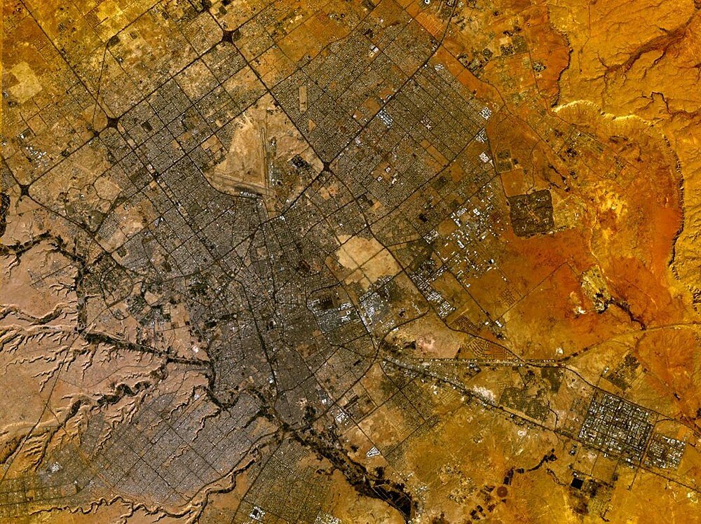 Aerial view of desert city with grid streets Aerial view of a sprawling desert city with grid-like street patterns and surrounding arid terrain