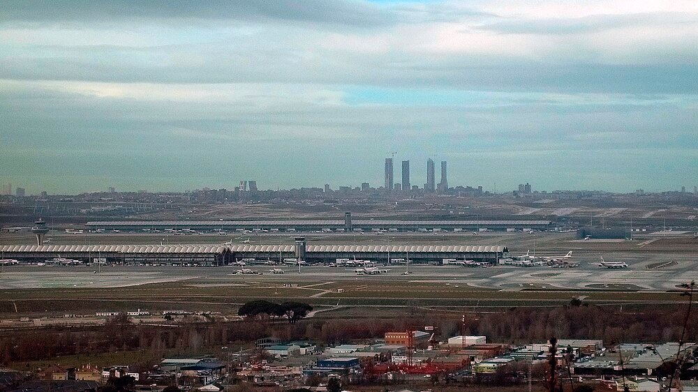 Aerial view of international airport with airplanes Aerial view of a large international airport with multiple airplanes and terminal buildings under a cloudy sky