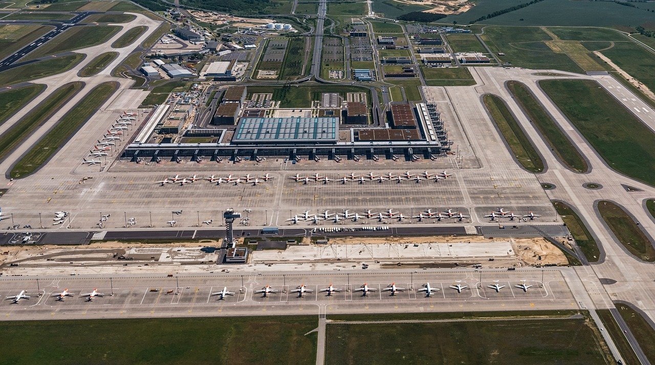 Aerial view of a large international airport with multiple airplanes parked at terminals and runways visible