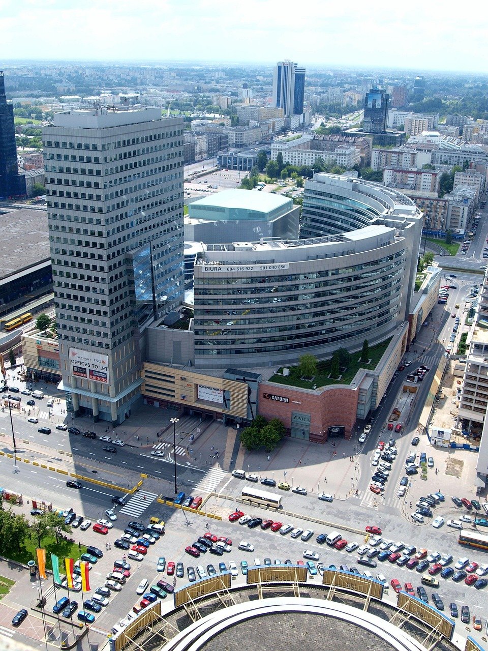 Aerial view of a modern urban cityscape with high-rise office buildings, busy streets, and parked cars in a commercial district.