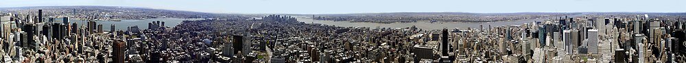Aerial panoramic view of urban city skyline Panoramic aerial view of a dense urban cityscape with skyscrapers, rivers, and bridges under a clear sky
