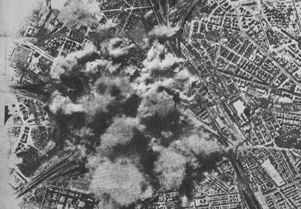 Aerial view of wartime urban explosion and smoke Aerial black and white photo showing a large explosion and smoke over an urban area during wartime bombing.