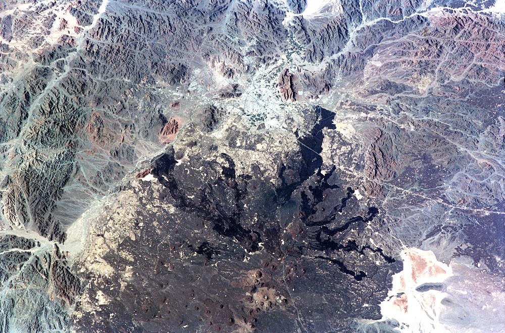 Aerial view of volcanic crater and mountains Aerial view of a volcanic crater surrounded by rugged mountainous terrain and sparse vegetation