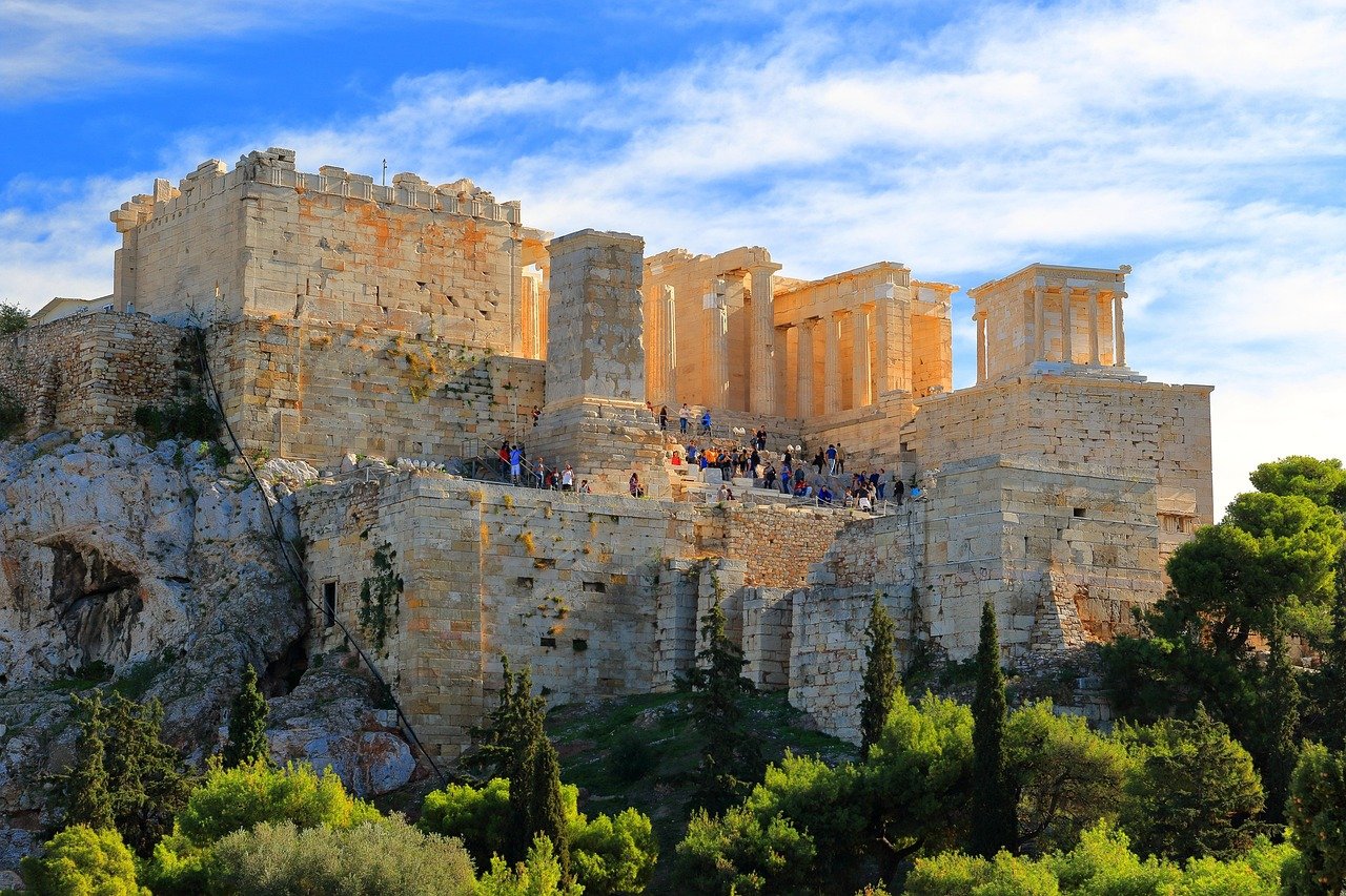 Ancient Acropolis of Athens with historic stone structures and tourists under a bright blue sky
