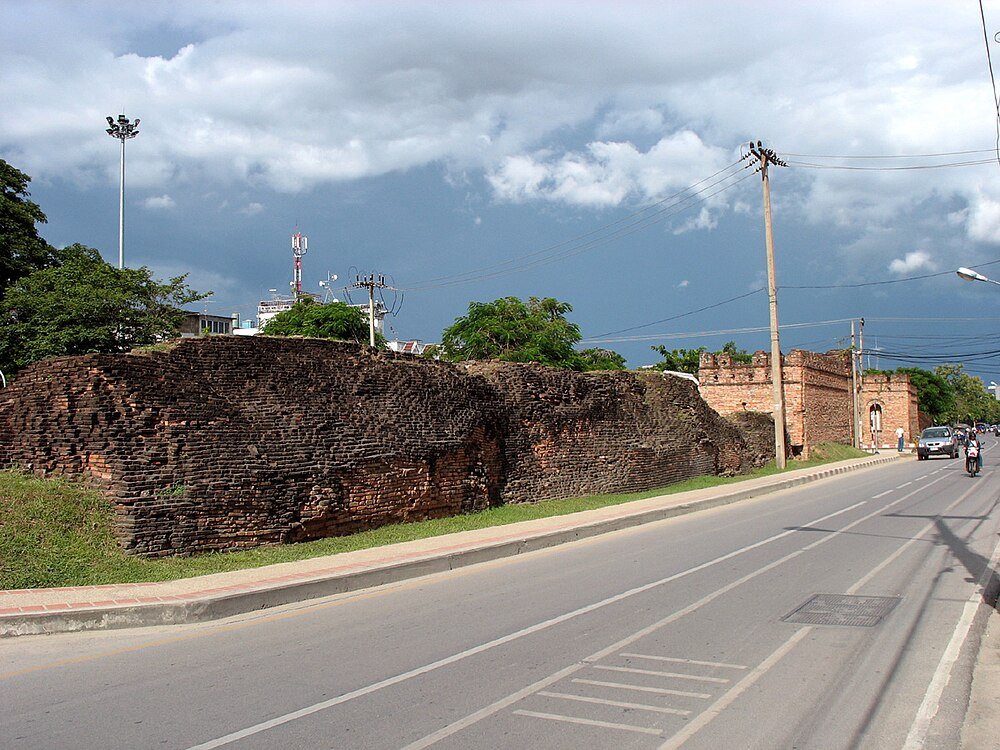 Ancient brick city wall by roadside Ancient brick city wall along roadside with cloudy sky and vehicles in urban area, historical landmark and travel destination