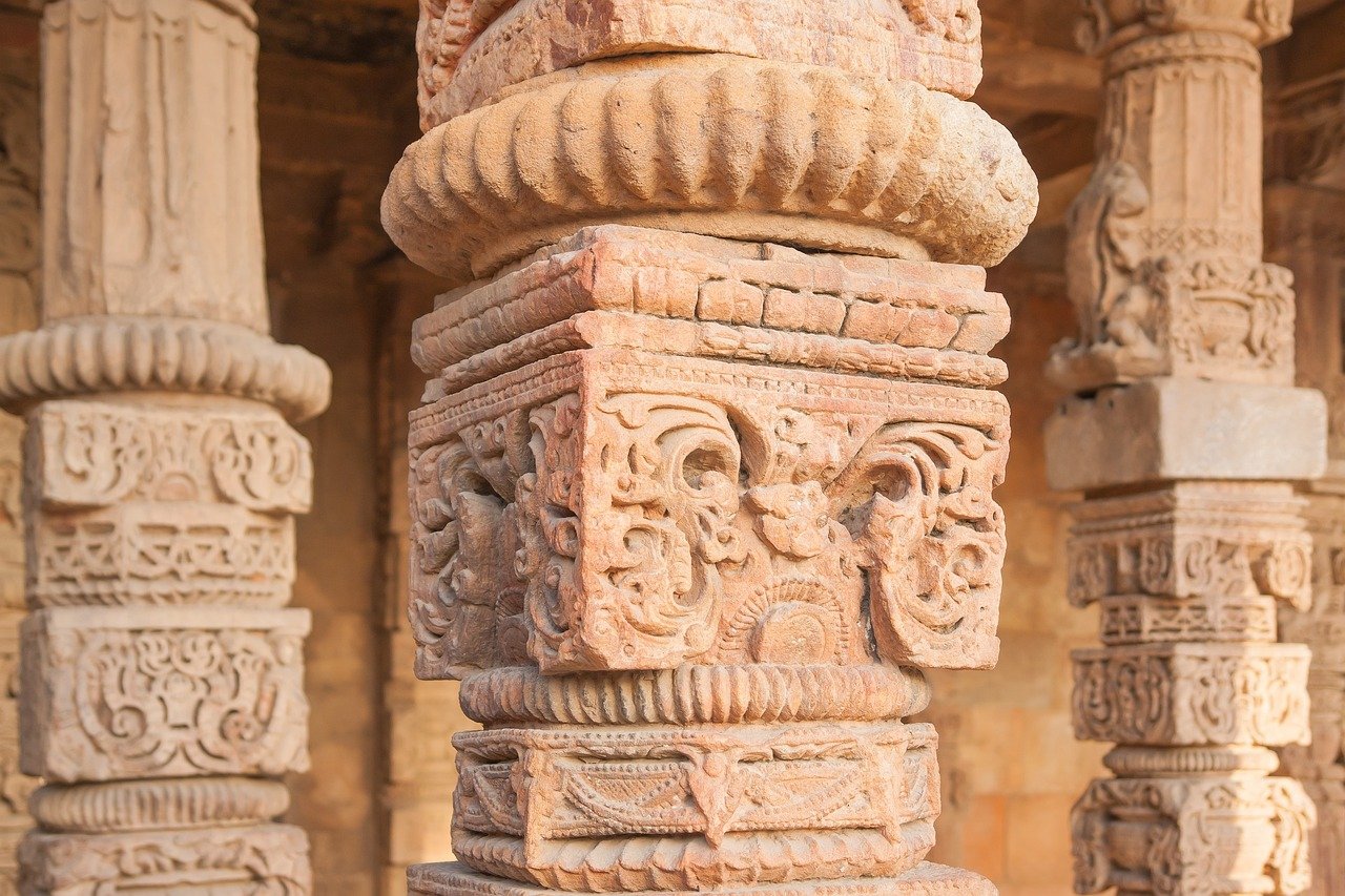 Intricately carved ancient sandstone pillars with detailed floral and geometric patterns in historic architecture
