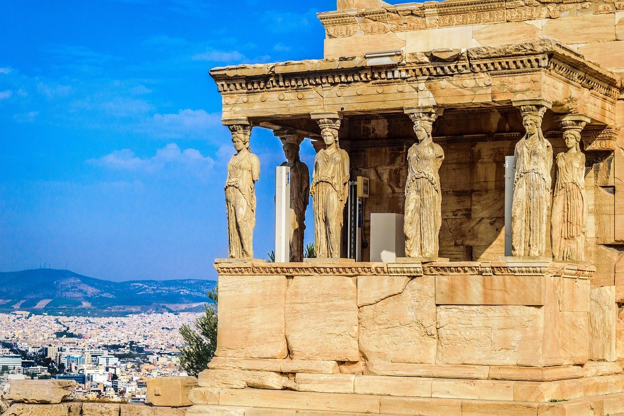 Ancient Greek Erechtheion temple with Caryatids statues overlooking Athens city and blue sky