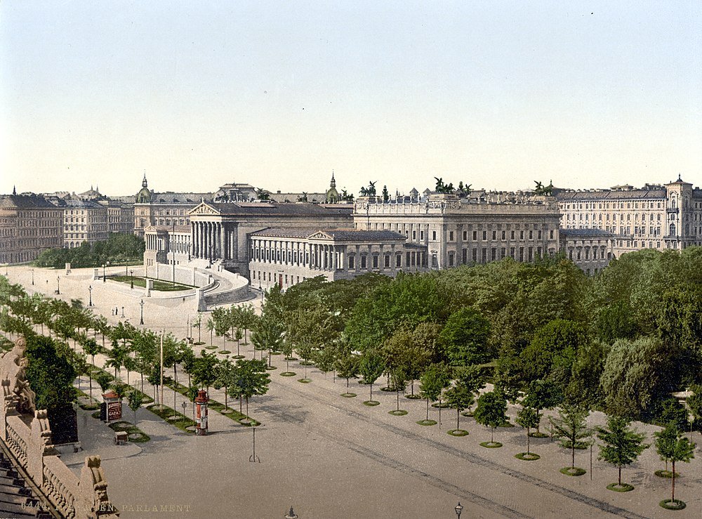 Historic view of the Austrian Parliament Building in Vienna with surrounding trees and classical architecture