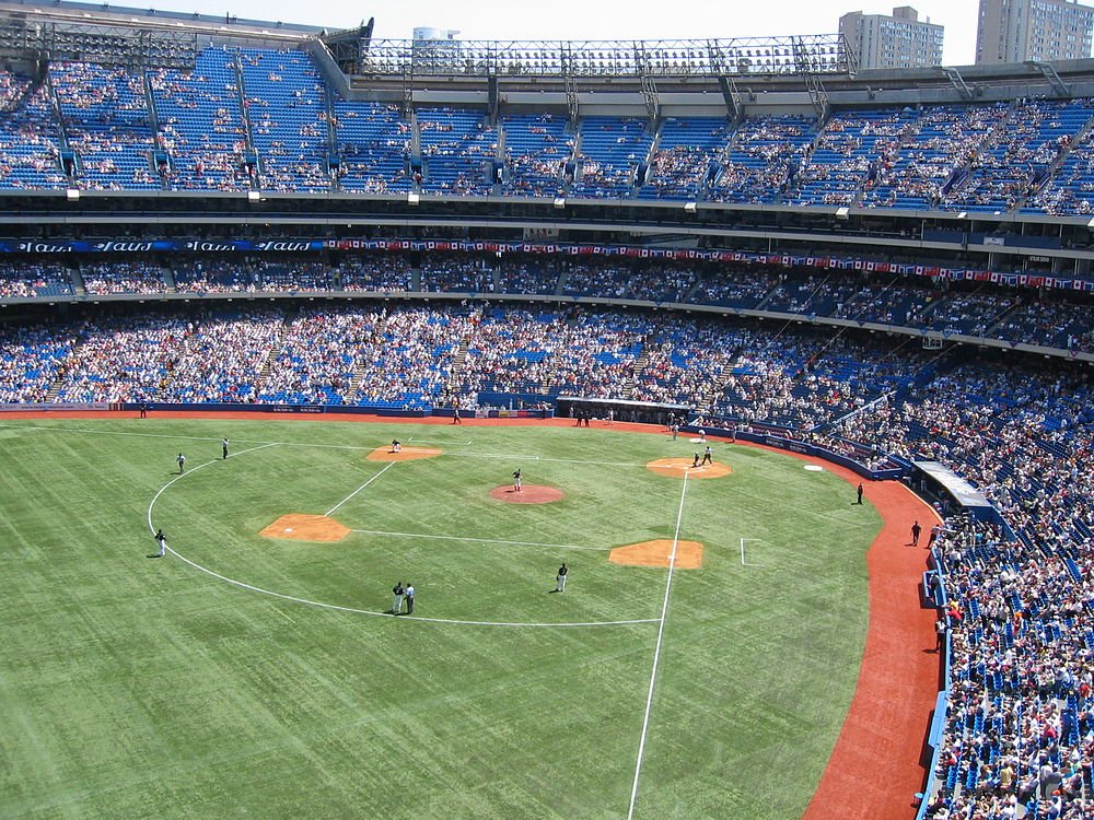 Baseball game in a crowded stadium A professional baseball game in a large stadium with many spectators and players on the field during daytime