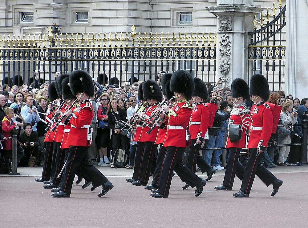 British Guards Marching at Buckingham Palace British guards in red uniforms and bearskin hats marching and playing instruments at Buckingham Palace ceremony