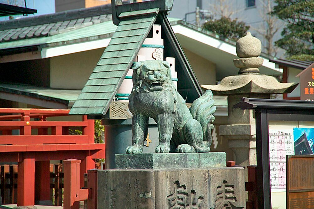Bronze Komainu Statue at Japanese Shrine Bronze komainu lion-dog statue at a traditional Japanese shrine with red wooden railings and stone lanterns