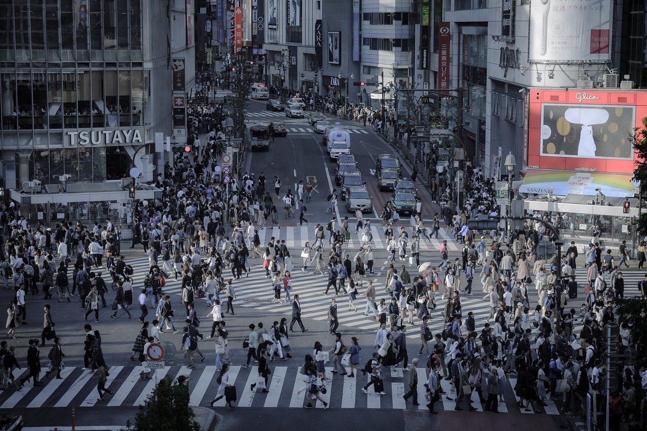 Busy urban pedestrian crossing with crowds of people and vehicles in a bustling city center during daytime
