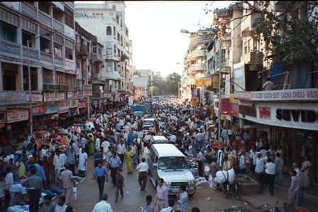 Busy Indian street market with crowds and vehicles Crowded busy street market in an Indian city with numerous pedestrians, vehicles, and shops on both sides during daytime