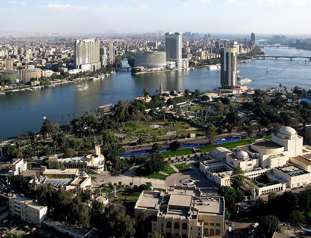 Cairo cityscape with Nile River and bridges Aerial view of Cairo cityscape with Nile River, bridges, high-rise buildings, and green park areas under clear sky