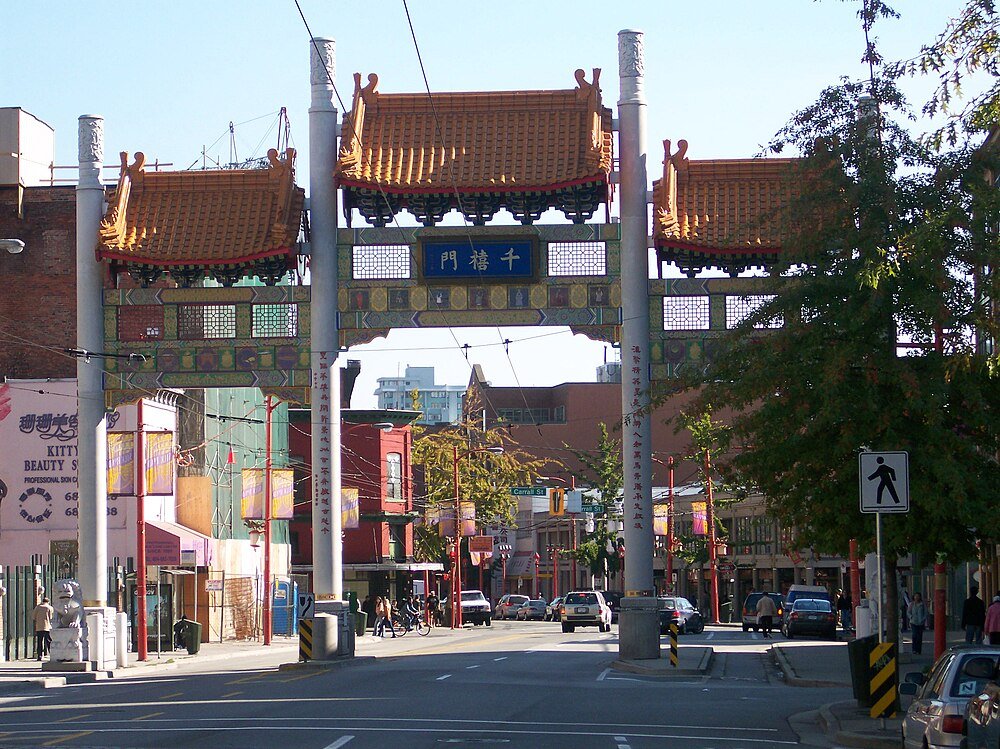 Chinese Archway Gate in Chinatown District Traditional Chinese archway gate in a busy urban Chinatown district with cars and pedestrians on the street