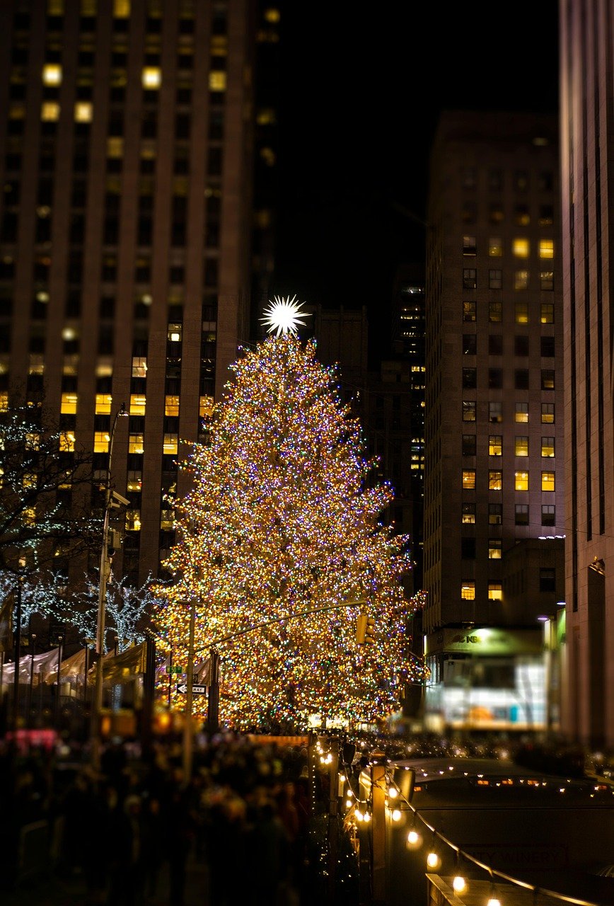 Large Christmas tree decorated with colorful lights and a bright star on top in a city square at night