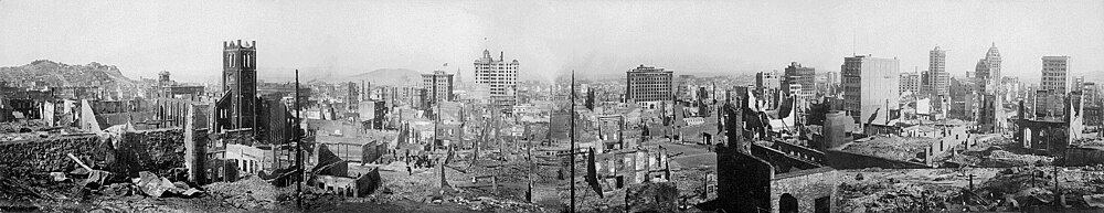 Panoramic view of city ruins after disaster Panoramic black and white photo of a city devastated by a large-scale fire or bombing, showing ruins and damaged buildings.