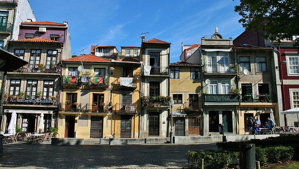 Colorful old residential buildings with balconies and outdoor seating in a sunny European street scene