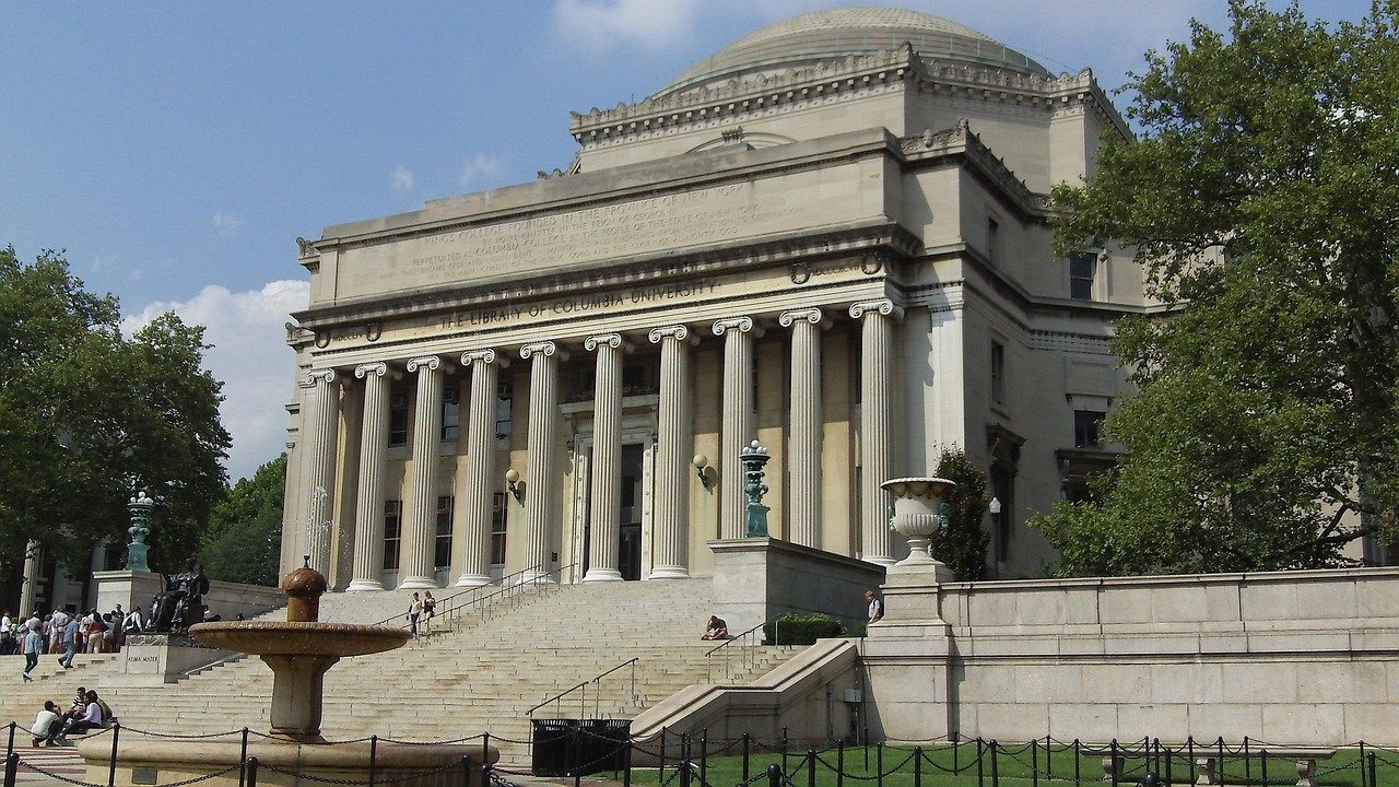 The iconic library building of Columbia University with grand columns and steps under a clear sky in New York City