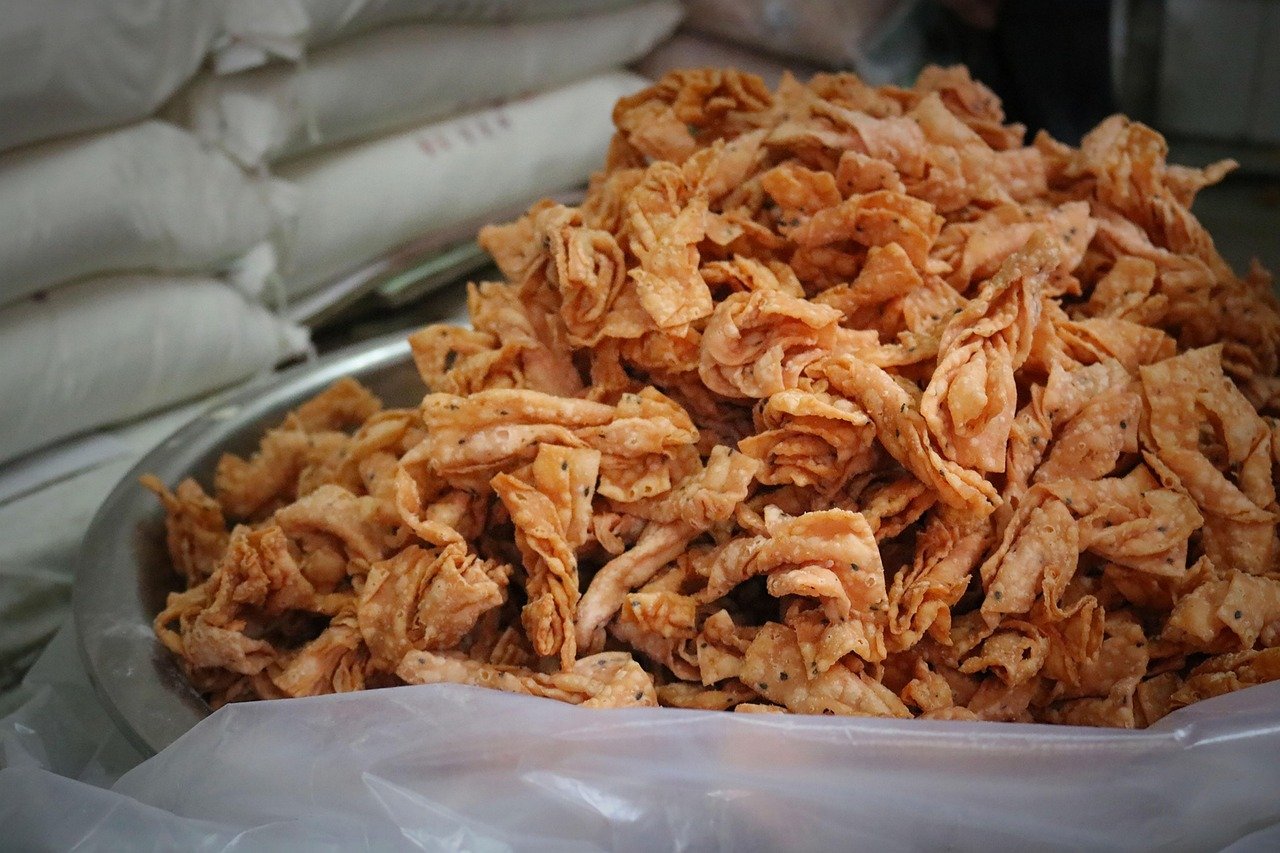 Close-up of a large bowl filled with crispy Indian snack called karanji or gujiya, made from fried dough with spices.
