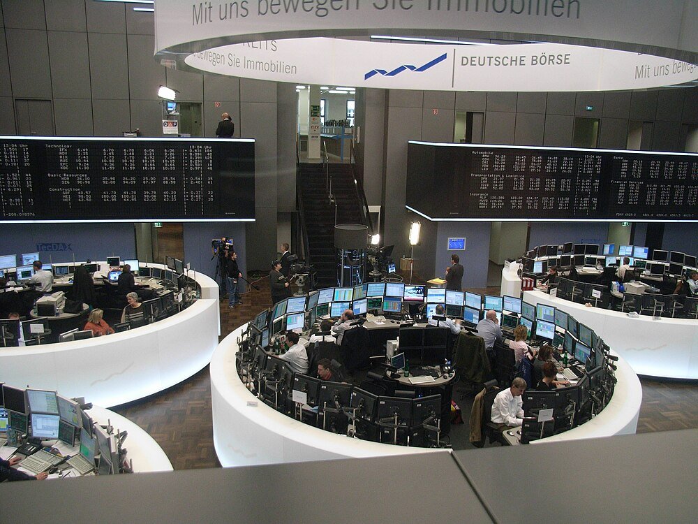 Deutsche Börse trading floor with stock price displays Traders working at Deutsche Börse stock exchange with multiple monitors and large electronic stock price boards