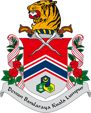 Coat of arms of Dewan Bandaraya Kuala Lumpur featuring a tiger head, crossed kris, and floral decorations with ribbons