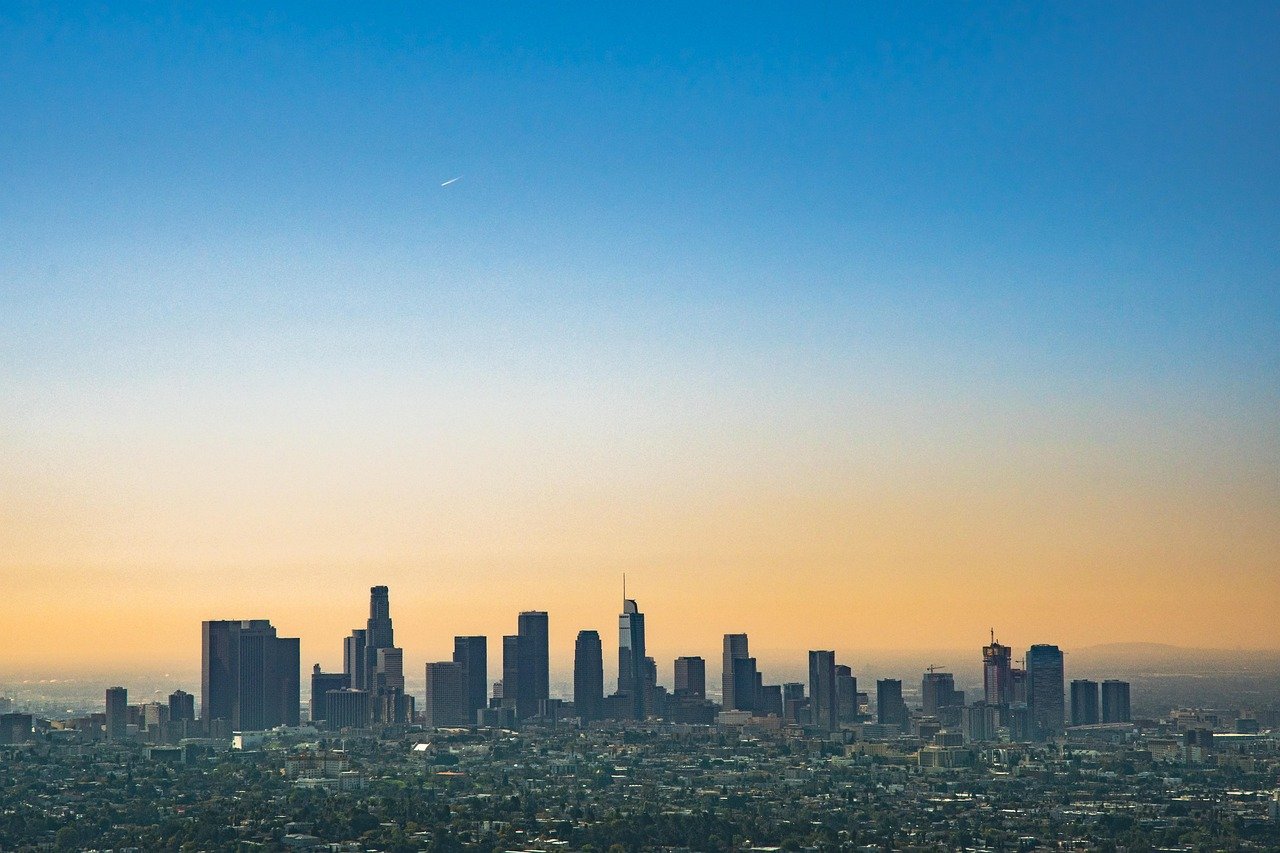 Panoramic view of downtown Los Angeles skyline with high-rise buildings under a clear blue sky at sunset