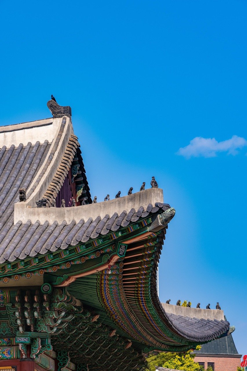 Traditional East Asian temple roof with ornate decorations and figurines under a clear blue sky