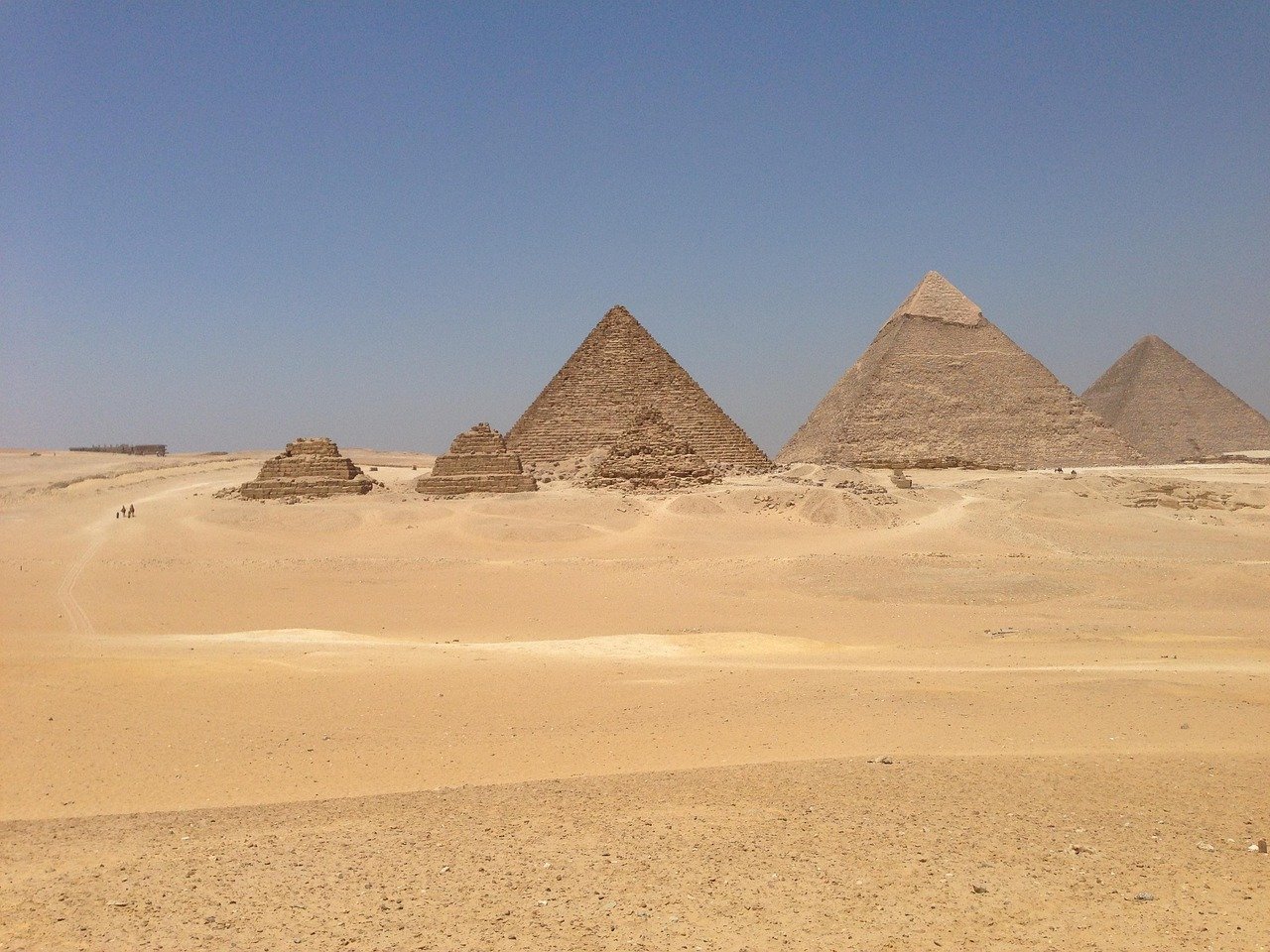 Ancient Egyptian pyramids in the desert under clear blue sky, showcasing historic Giza pyramid complex architecture