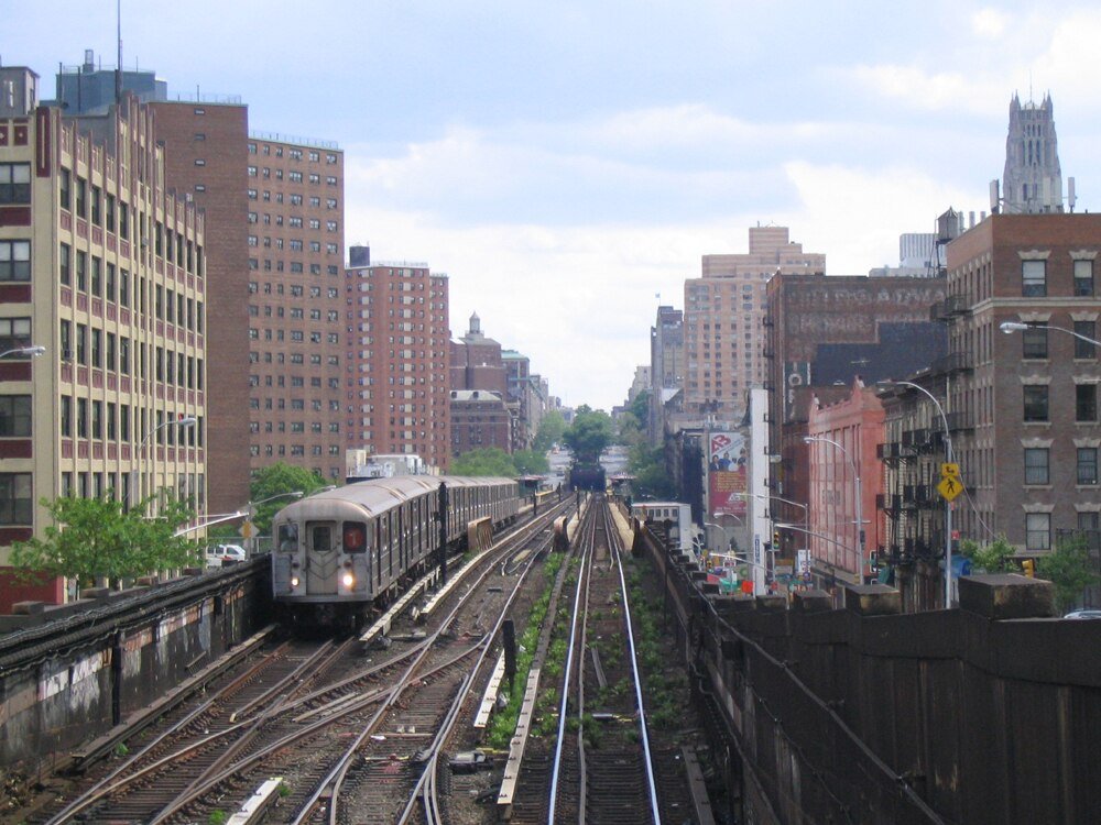 Elevated subway train in urban cityscape Elevated subway train on tracks passing through urban cityscape with tall buildings and cloudy sky