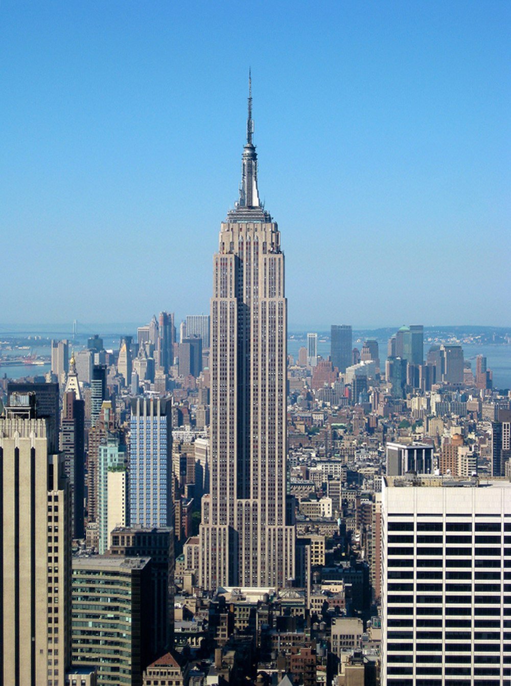 Empire State Building in New York City skyline Empire State Building towering over New York City skyline on a clear sunny day with blue sky background
