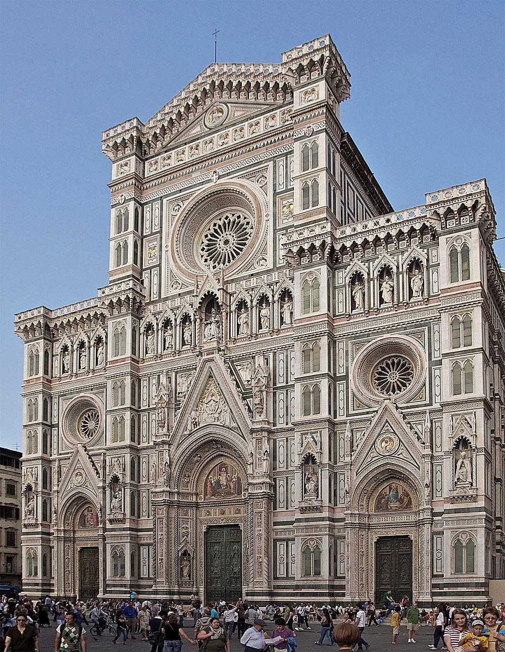 Facade of Florence Cathedral with intricate Gothic architecture and crowds of tourists in Florence, Italy