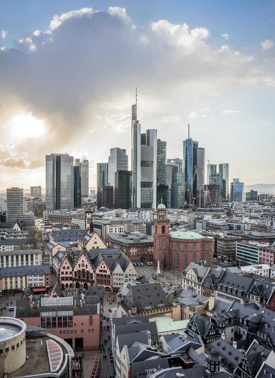 Skyline of Frankfurt am Main with modern skyscrapers and historic buildings under a cloudy sky at sunset