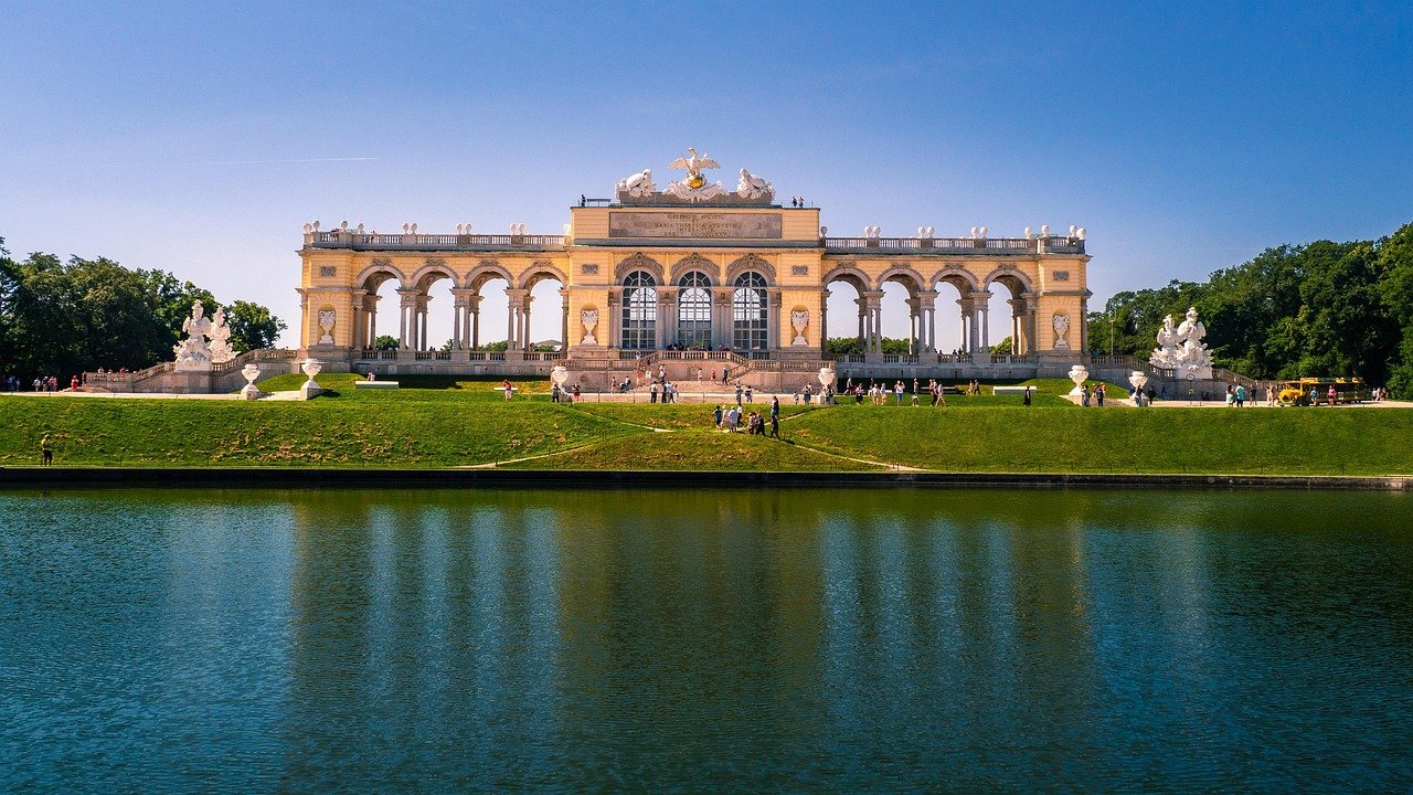 Gloriette structure in Schönbrunn Palace gardens with blue sky and reflecting pond in Vienna, Austria