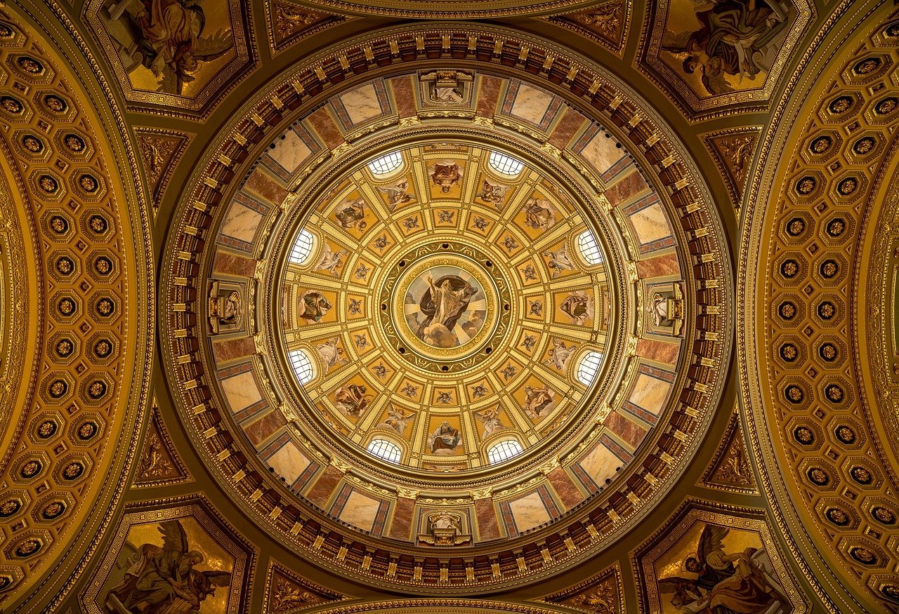 Intricately decorated golden dome ceiling with religious frescoes and ornate architectural details in a historic building