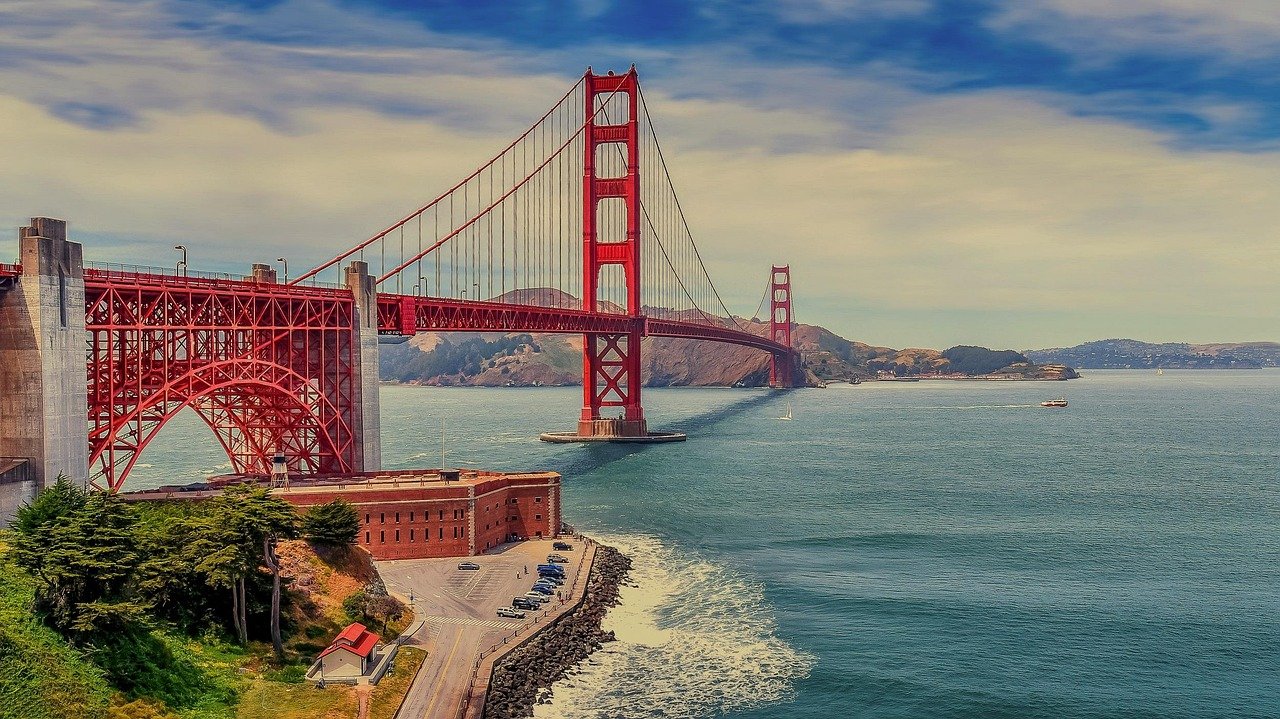 Golden Gate Bridge in San Francisco spanning over the blue water with clear sky and distant hills