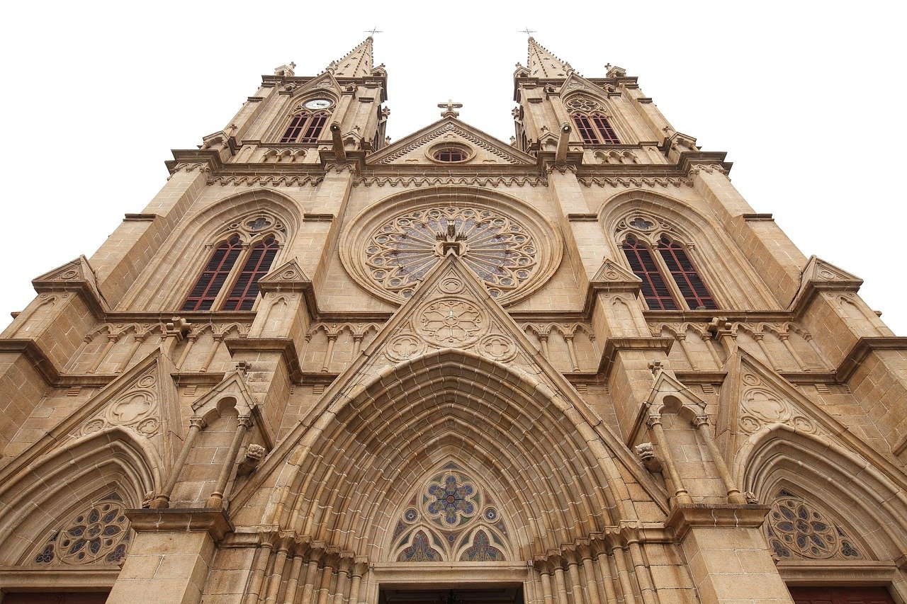 Gothic cathedral facade with twin spires, arched windows, and intricate stone carvings under a clear sky