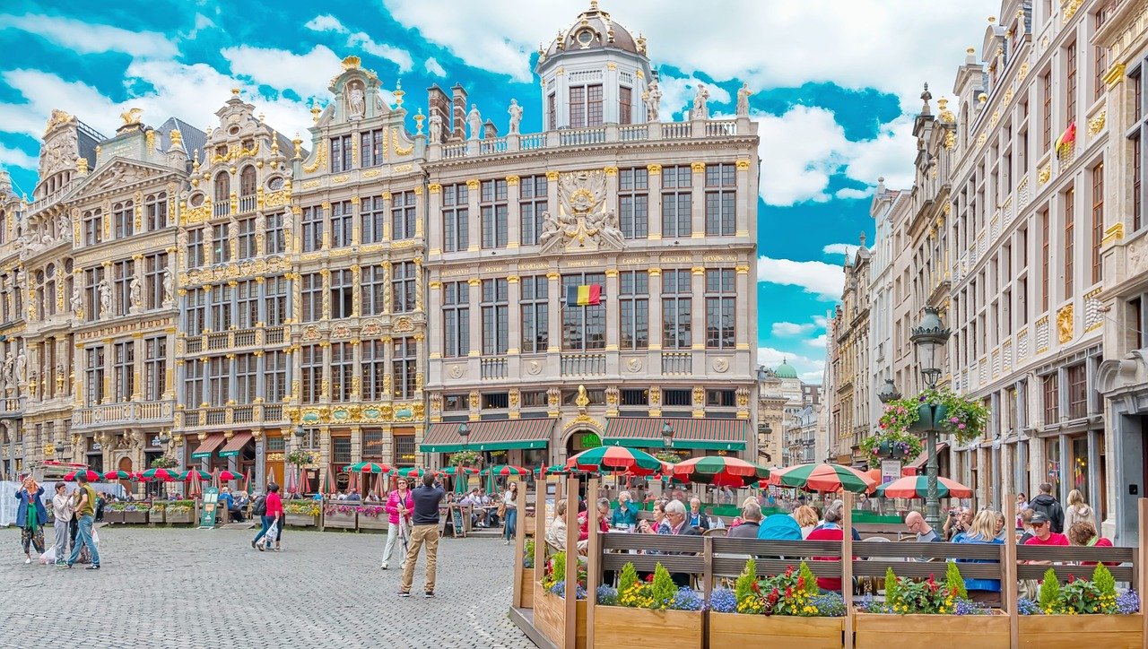 Historic Grand Place square in Brussels with ornate guildhalls, outdoor cafes, and people enjoying a sunny day