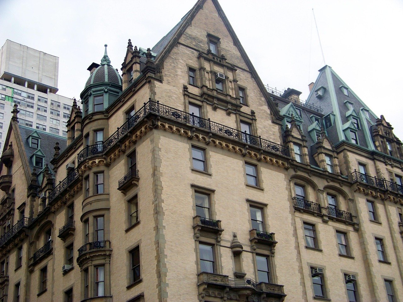Historic beige brick building with ornate architectural details and green copper roof in urban cityscape
