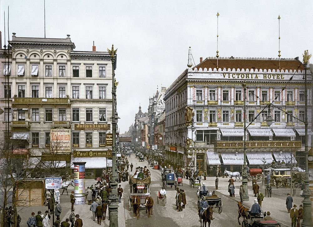 Early 20th Century City Street with Victoria Hotel Historic city street scene with horse-drawn carriages, pedestrians, and Victoria Hotel building in early 20th century Europe