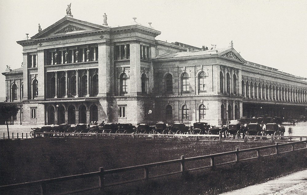 Historic building with horse-drawn carriages Historic black and white photo of a large classical building with horse-drawn carriages parked outside