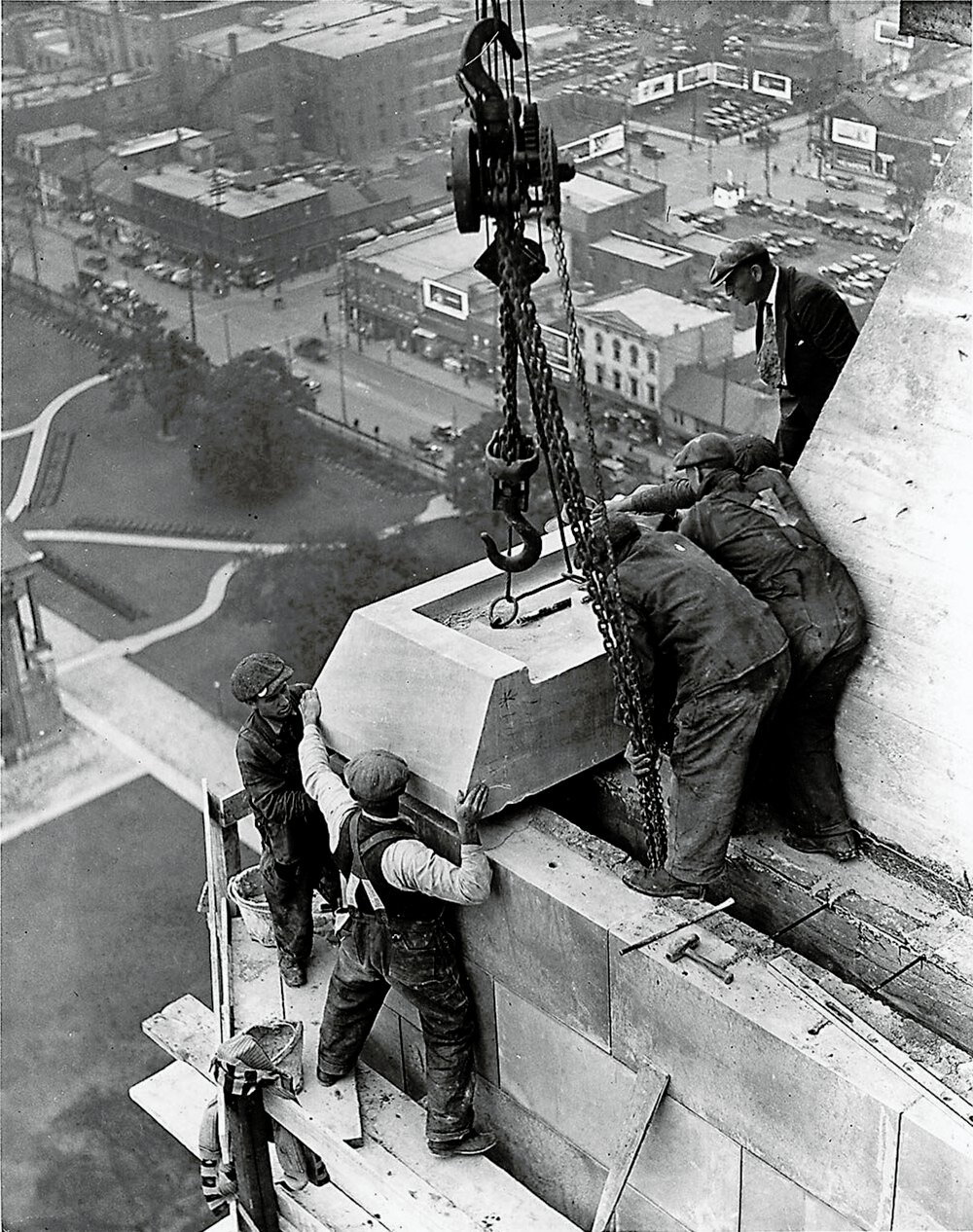 Construction workers installing stone blocks on skyscraper Historic black and white photo of construction workers installing large stone blocks on a high-rise building facade