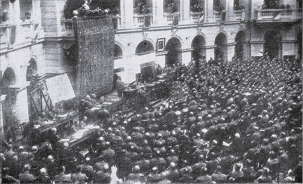 Historic crowd at outdoor formal event in courtyard Historic black and white photo of a large crowd attending an outdoor formal event in a courtyard with arches