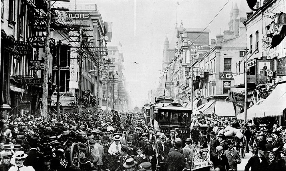 Crowded early 20th century city street with trolley cars Historic black and white photo of a crowded city street with early 20th century trolley cars and pedestrians