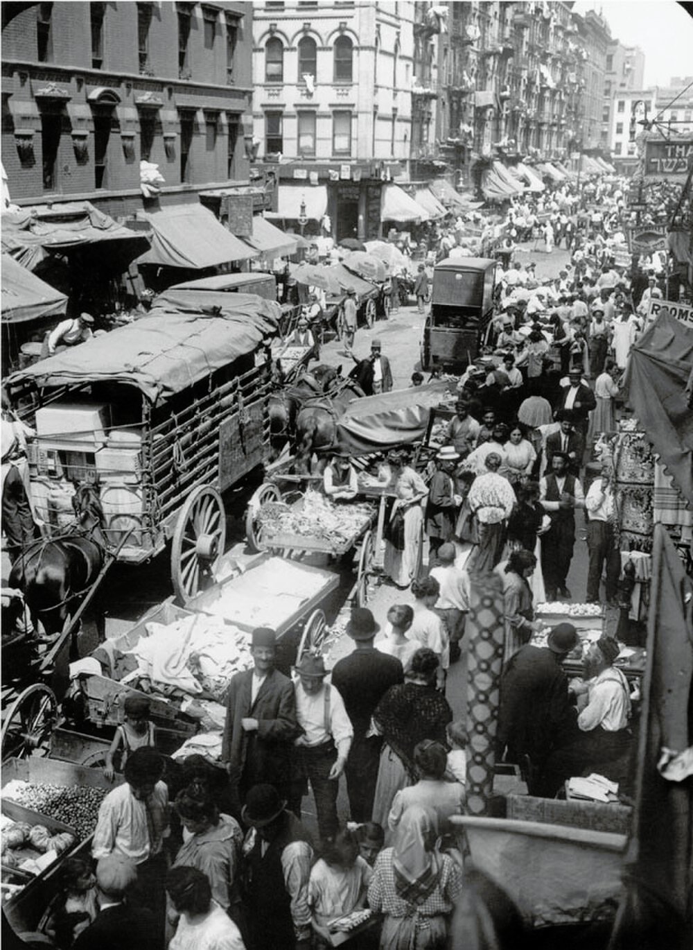 Crowded historic street market with horse-drawn carts Historic black and white photo of a crowded street market with horse-drawn carts and many people shopping
