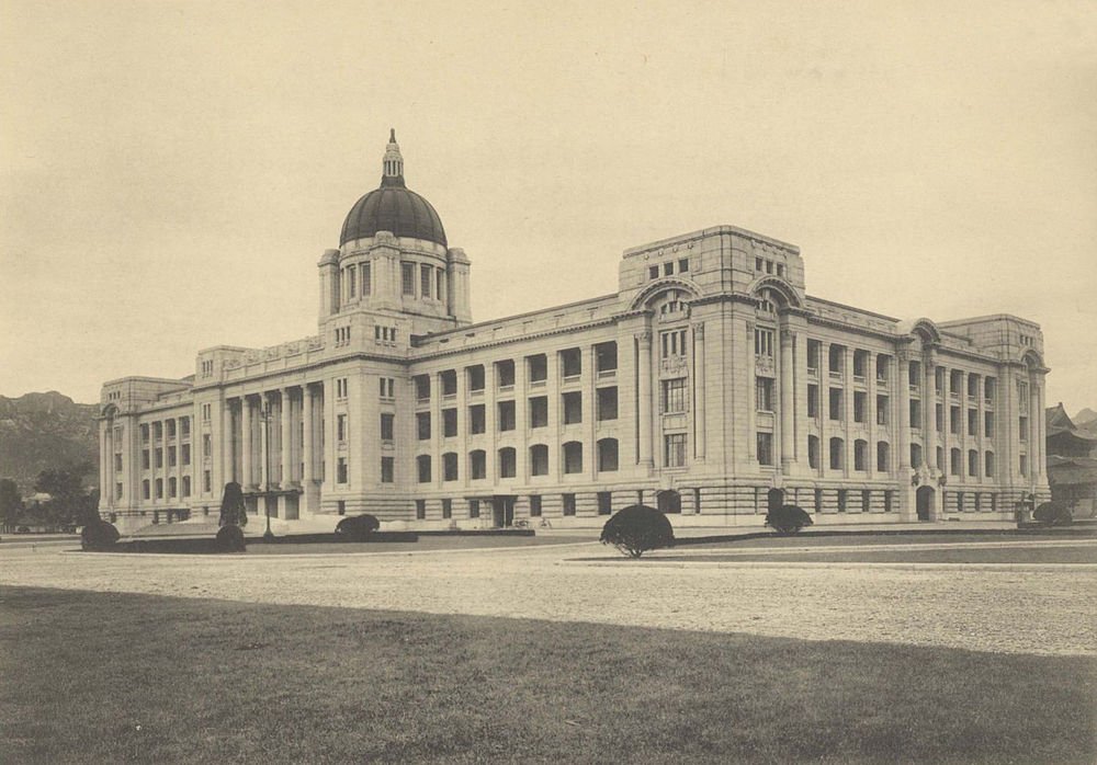 Historic government building with dome and columns Historic government building with classical architecture and a large dome, surrounded by manicured lawns and trees.