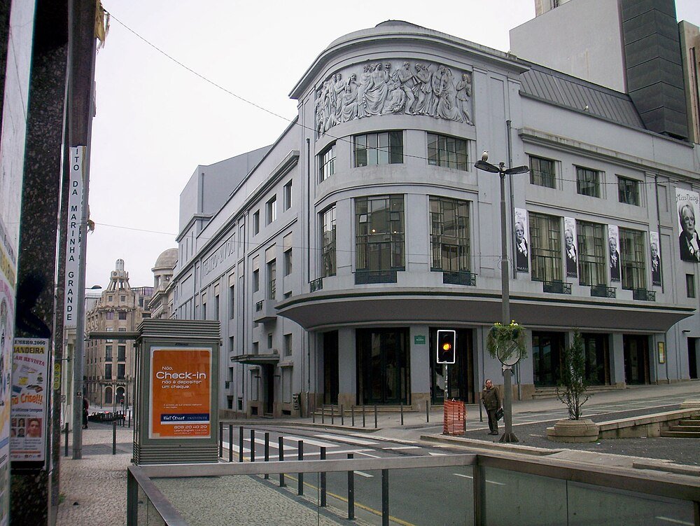 Historic gray building with sculptures and windows Historic gray building with classical sculptures and large windows on a city street with pedestrian and traffic light