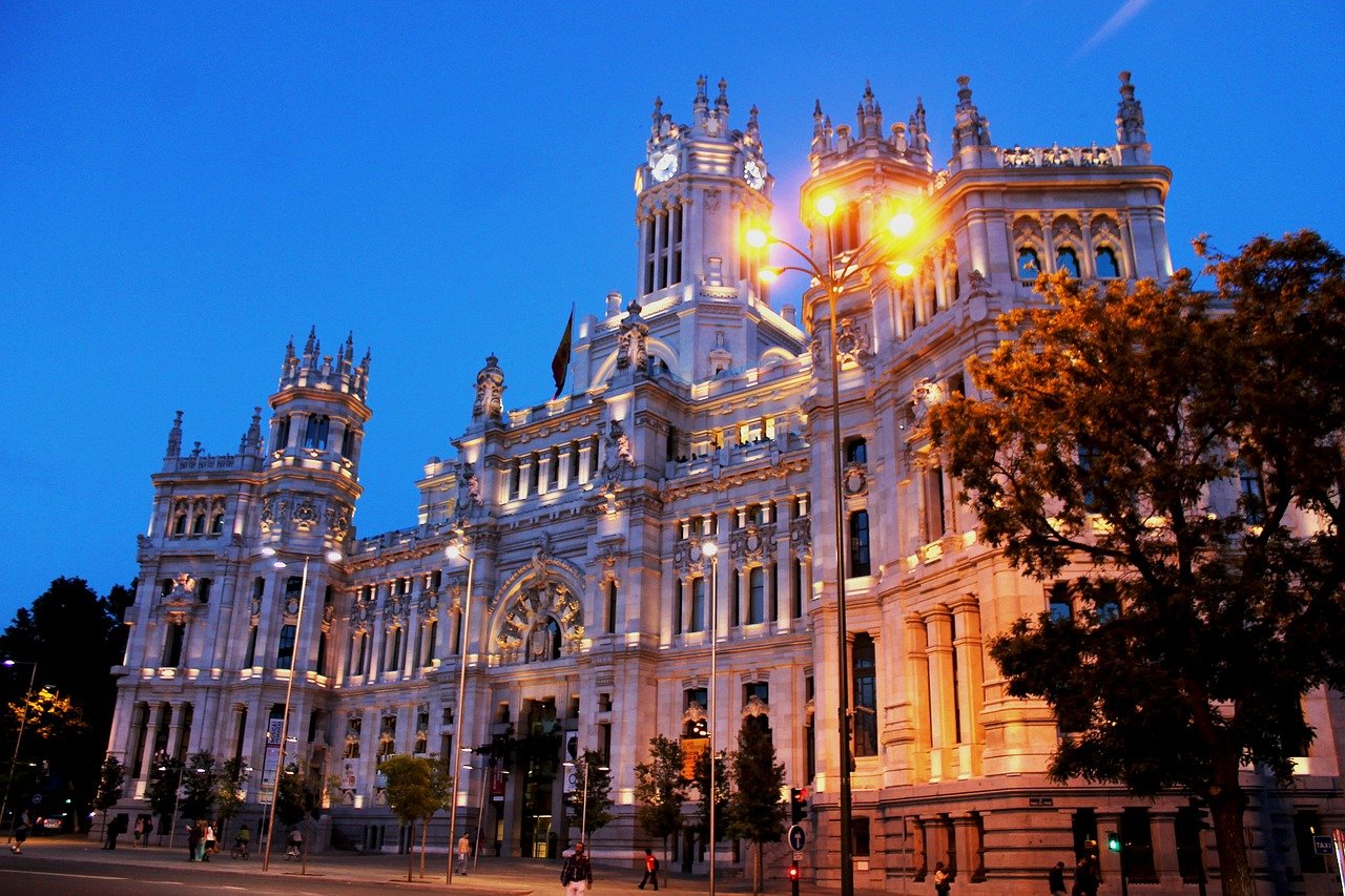 Illuminated historic building with ornate architecture and clock towers at dusk in a European city