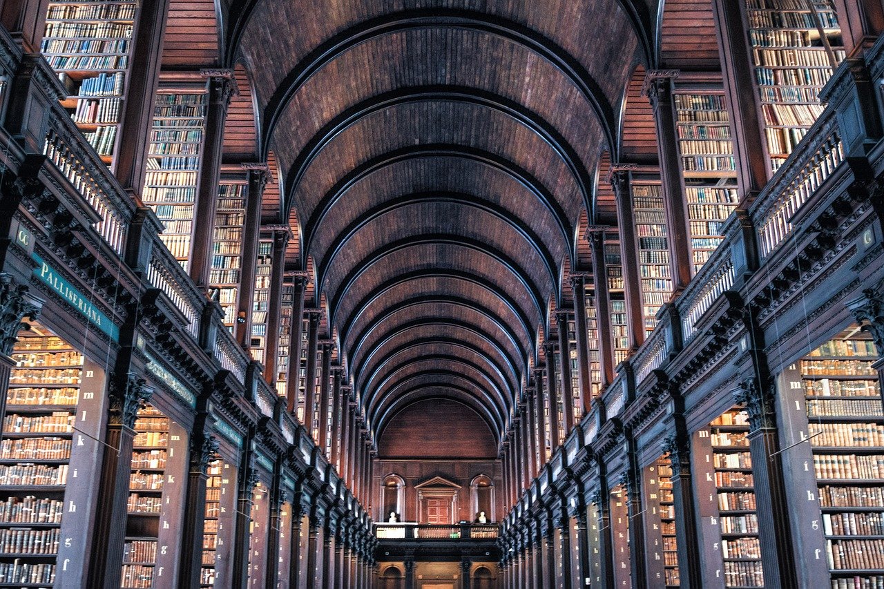 Interior view of a grand historic library with tall wooden bookshelves and arched ceiling filled with old books